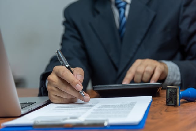 A man holding a pen over paperwork on a desk, ready to sign or prepare legal documents at Fingerscan Digital Inc in Las Vegas.