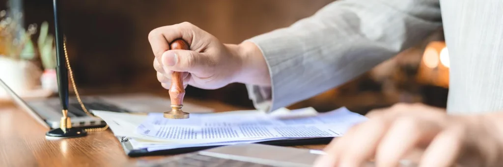 Hand stamping official document on a desk, symbolizing FBI background check apostille process.