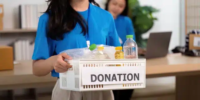 Bay Area nonprofit volunteer with donation box - AB 506 youth-serving organization